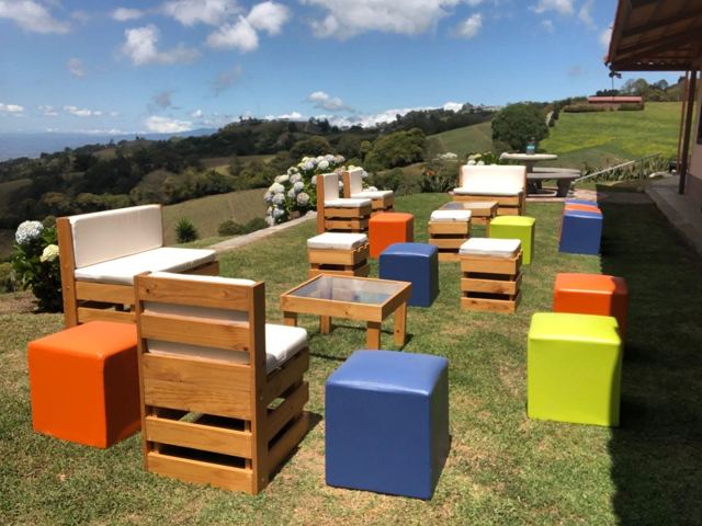 Lounge de pallet con cubos de colores en jardín con vista