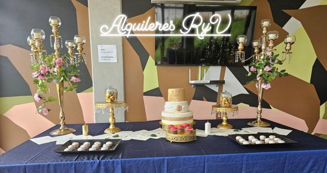 Mesa de postres con mantel azul y candelabros dorados
