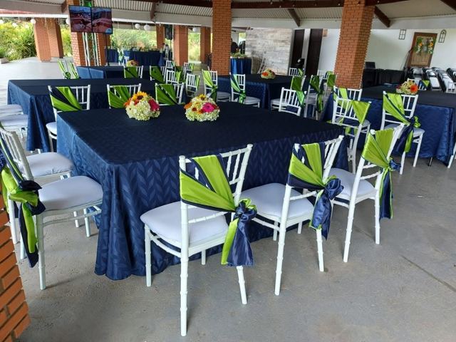 Mesas con mantel azul marino y sillas Tiffany blancas con lazo verde