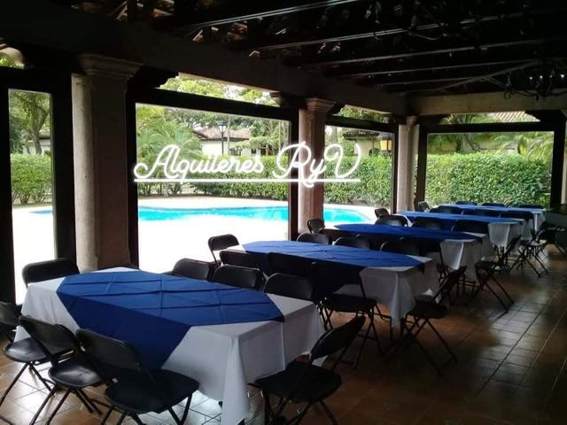 Mesas rectangulares mantel blanco con sobremantel azul junto a piscina