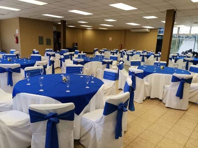 Salón con sillas forradas blancas lazo azul y mesas redondas