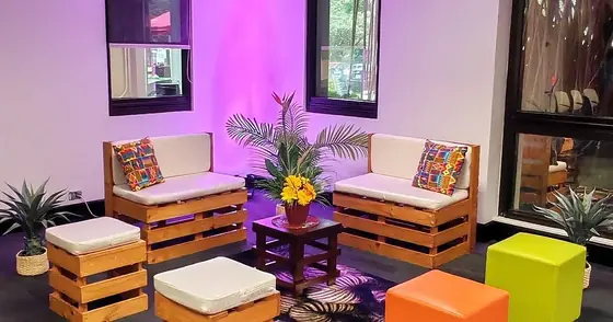 Sala lounge de tarimas de madera con cojines y cubos de colores