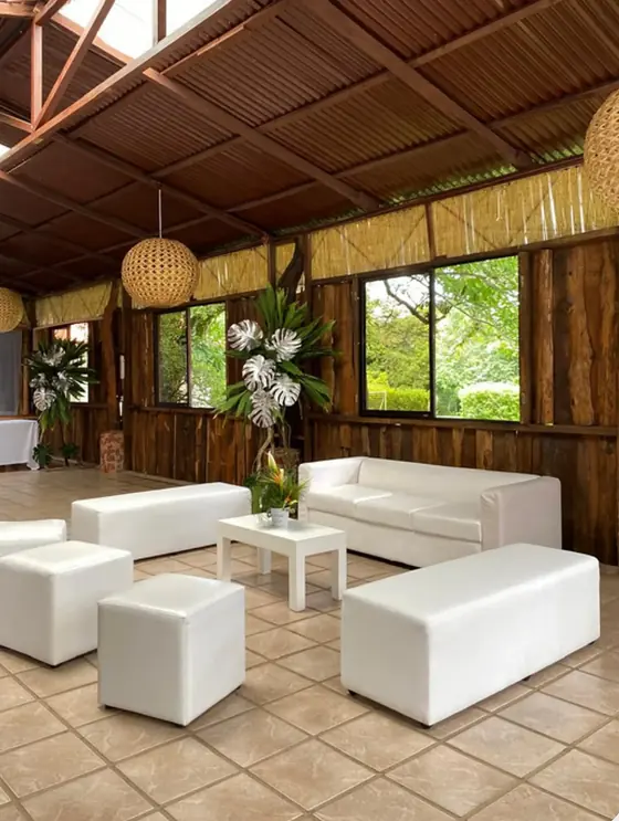 Sala lounge blanca con sillones, cubos y mesa de centro en un rancho