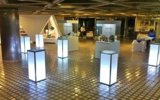 Mesas cocteleras iluminadas en un salón para un evento de empresa